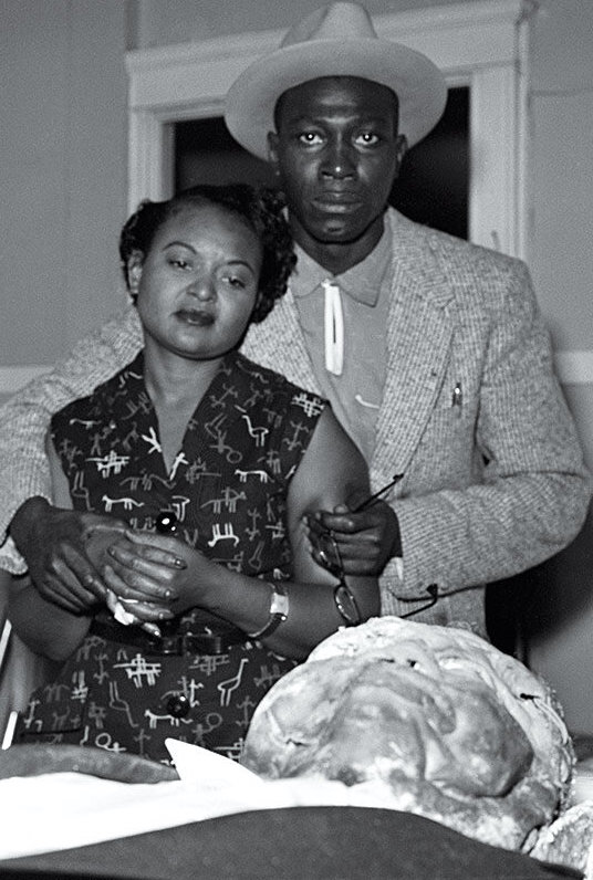 Mamie Till looks over the body of her son Emmett Till at the morgue before his funeral. With her is her fiancé, Gene Mobley. First published in Jet magazine, September 15, 1955. Photo by David Jackson. This photo is in the public domain.